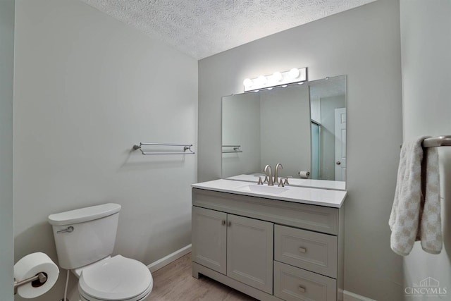 8750 E Kemper Rd, Symmes Twp, OH 45249 - bathroom featuring baseboards, a textured ceiling, vanity, toilet, and wood finished floors