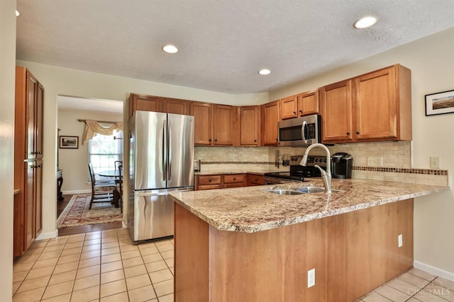 8750 E Kemper Rd, Symmes Twp, OH 45249 - kitchen featuring appliances with stainless steel finishes, a sink, a peninsula, light tile patterned floors, and brown cabinets