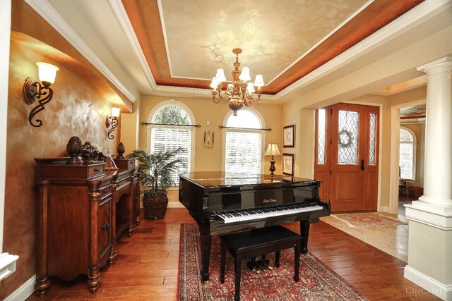 4625 Guildford Dr, West Chester, OH 45069 - living area featuring ornate columns, a tray ceiling, dark wood-type flooring, and a chandelier