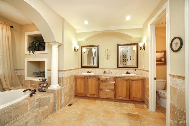 4625 Guildford Dr, West Chester, OH 45069 - full bathroom featuring tile walls, decorative columns, toilet, double vanity, and a bath