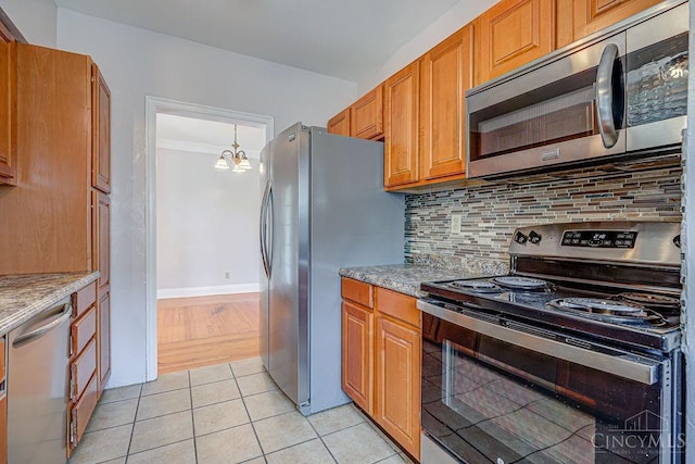 3947 Ruth Ln, Cheviot, OH 45211 - kitchen featuring appliances with stainless steel finishes, backsplash, a chandelier, light tile patterned floors, and brown cabinetry
