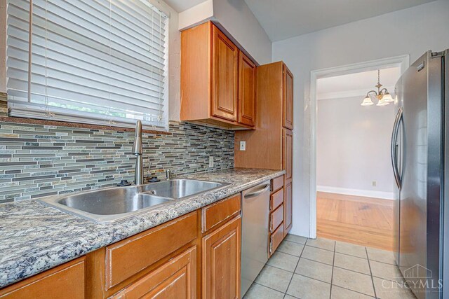 3947 Ruth Ln, Cheviot, OH 45211 - kitchen featuring stainless steel appliances, brown cabinetry, tasteful backsplash, light tile patterned floors, and a chandelier