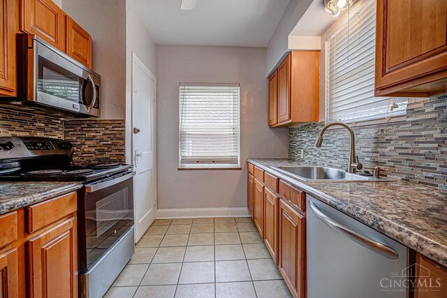 3947 Ruth Ln, Cheviot, OH 45211 - kitchen with appliances with stainless steel finishes, backsplash, light tile patterned floors, and brown cabinets
