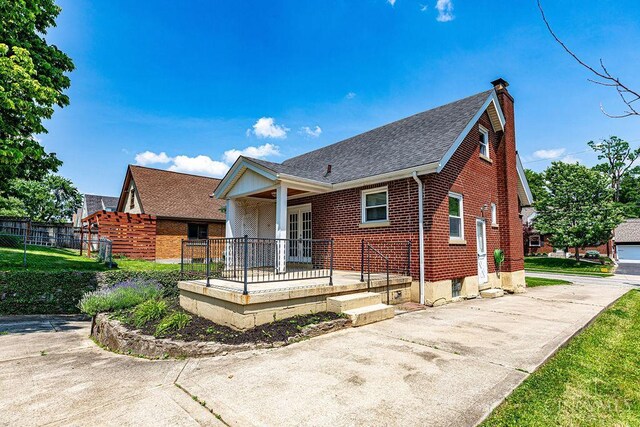 3947 Ruth Ln, Cheviot, OH 45211 - view of front of house with a porch, a chimney, brick siding, and roof with shingles