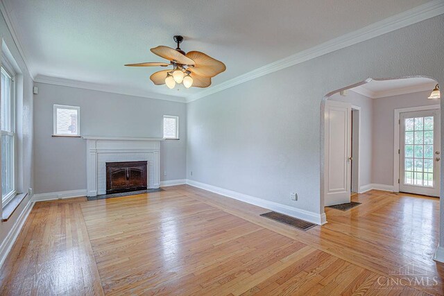 3947 Ruth Ln, Cheviot, OH 45211 - unfurnished living room with arched walkways, light wood-type flooring, a brick fireplace, a ceiling fan, and ornamental molding