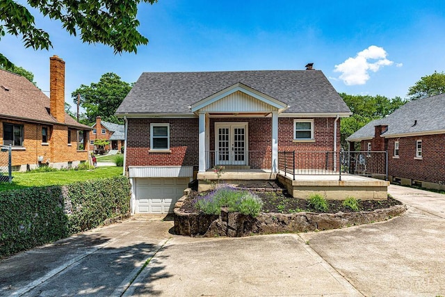 3947 Ruth Ln, Cheviot, OH 45211 - view of front facade with french doors, brick siding, driveway, an attached garage, and roof with shingles