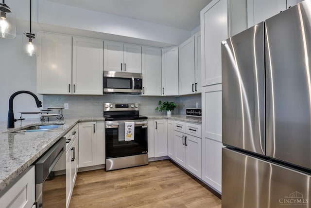 2351 Concord St, Cincinnati, OH 45206 - kitchen with stainless steel appliances, white cabinetry, decorative backsplash, light wood-type flooring, and light stone counters