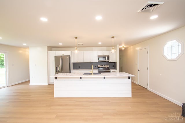 106 Fiord Dr, Lakengren, OH 45320 - kitchen with appliances with stainless steel finishes, a kitchen island with sink, a sink, light countertops, and white cabinetry