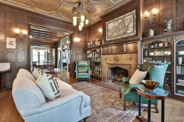 2334 Upland Pl, Cincinnati, OH 45206 - living area featuring a chandelier, wood walls, a fireplace, wood finished floors, and crown molding