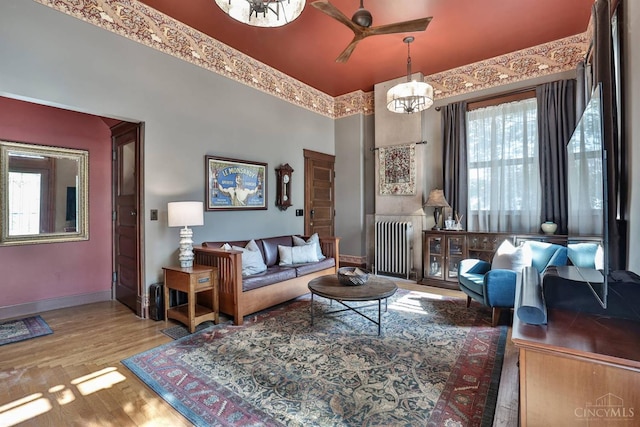 2334 Upland Pl, Cincinnati, OH 45206 - living room featuring radiator heating unit, a high ceiling, a ceiling fan, wood finished floors, and a chandelier