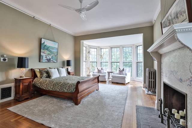 2334 Upland Pl, Cincinnati, OH 45206 - bedroom featuring ornamental molding, a brick fireplace, a ceiling fan, and wood finished floors