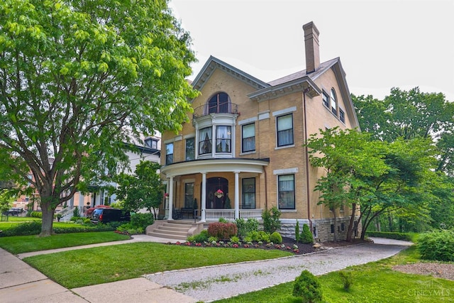 2334 Upland Pl, Cincinnati, OH 45206 - victorian-style house featuring covered porch, a front lawn, stone siding, a balcony, and a chimney