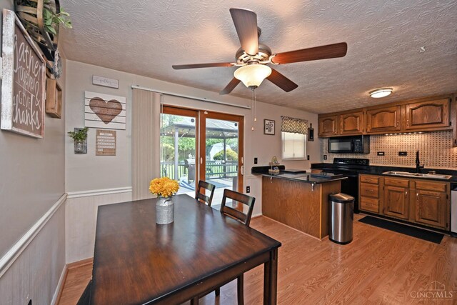 2868 Grosvenor Dr, Colerain Twp, OH 45251 - dining area with light wood-style floors, a ceiling fan, a textured ceiling, and wainscoting