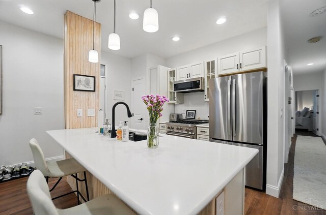 983 Paradrome St Unit A, Cincinnati, OH 45202 - kitchen featuring stainless steel appliances, dark wood-style floors, a kitchen bar, decorative light fixtures, and white cabinets