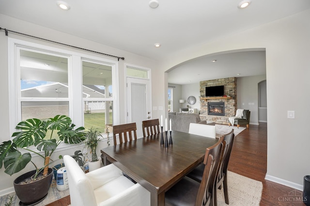 3779 Sturbridge Way, Pierce Twp, OH 45245 - dining room with arched walkways, dark wood-type flooring, a stone fireplace, and baseboards