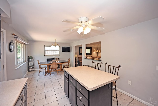 3430 Melodymanor Dr, Colerain Twp, OH 45239 - kitchen with a kitchen breakfast bar, light countertops, light tile patterned floors, ceiling fan, and a kitchen island