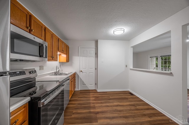 3721 W Galbraith Rd Unit A-2, Cincinnati, OH 45247 - kitchen with appliances with stainless steel finishes, a sink, brown cabinetry, dark wood-style flooring, and a textured ceiling