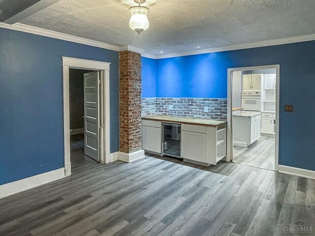 1588 Moon Valley Ln, Anderson Twp, OH 45230 - unfurnished room with wine cooler, wood finished floors, crown molding, and a textured ceiling