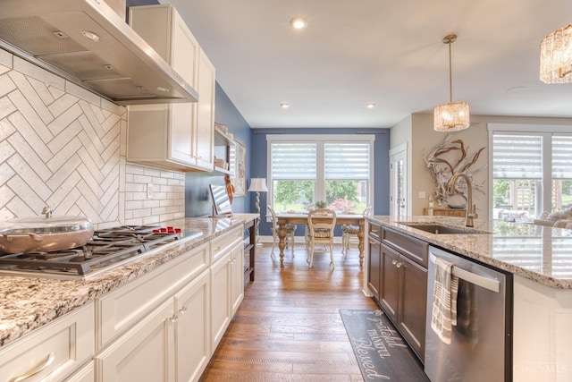 2645 Autumn Harvest Dr, Deerfield Twp, OH 45140 - kitchen featuring appliances with stainless steel finishes, wall chimney range hood, tasteful backsplash, wood finished floors, and hanging light fixtures