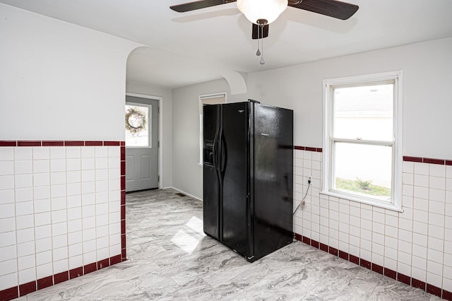 6643 Epworth Rd, Miami Twp, OH 45140 - kitchen with black refrigerator with ice dispenser, tile walls, a ceiling fan, light marble finish floors, and a wainscoted wall