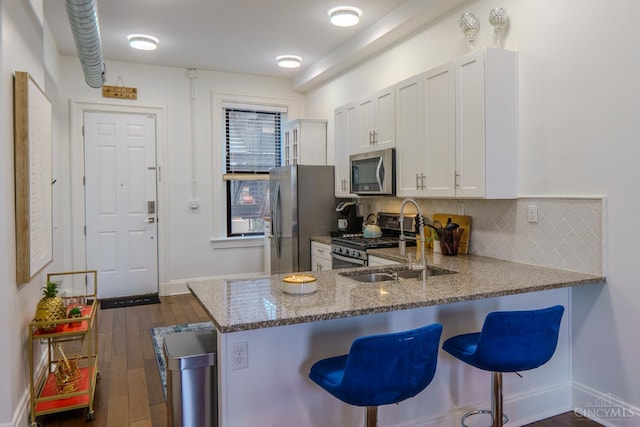 306 Mulberry St Unit 2, Cincinnati, OH 45202 - kitchen with appliances with stainless steel finishes, a breakfast bar, backsplash, dark stone counters, and dark wood finished floors