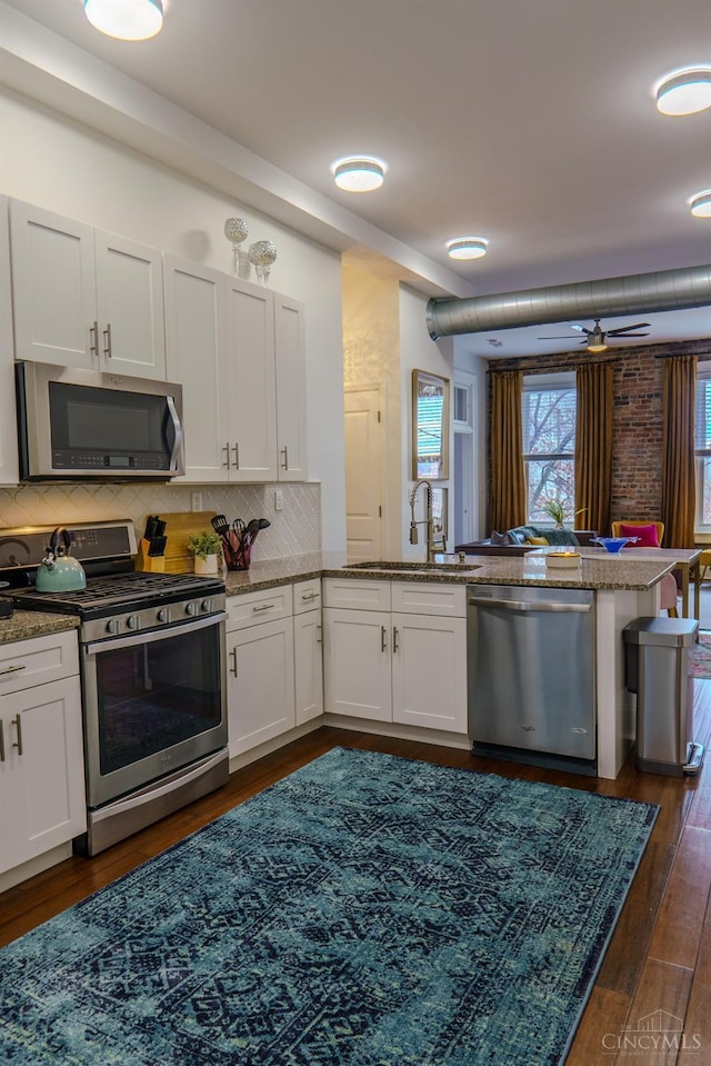 306 Mulberry St Unit 2, Cincinnati, OH 45202 - kitchen featuring appliances with stainless steel finishes, a peninsula, white cabinets, backsplash, and light stone countertops