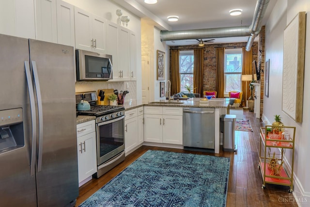 306 Mulberry St Unit 2, Cincinnati, OH 45202 - kitchen with appliances with stainless steel finishes, a peninsula, ceiling fan, light stone counters, and white cabinetry