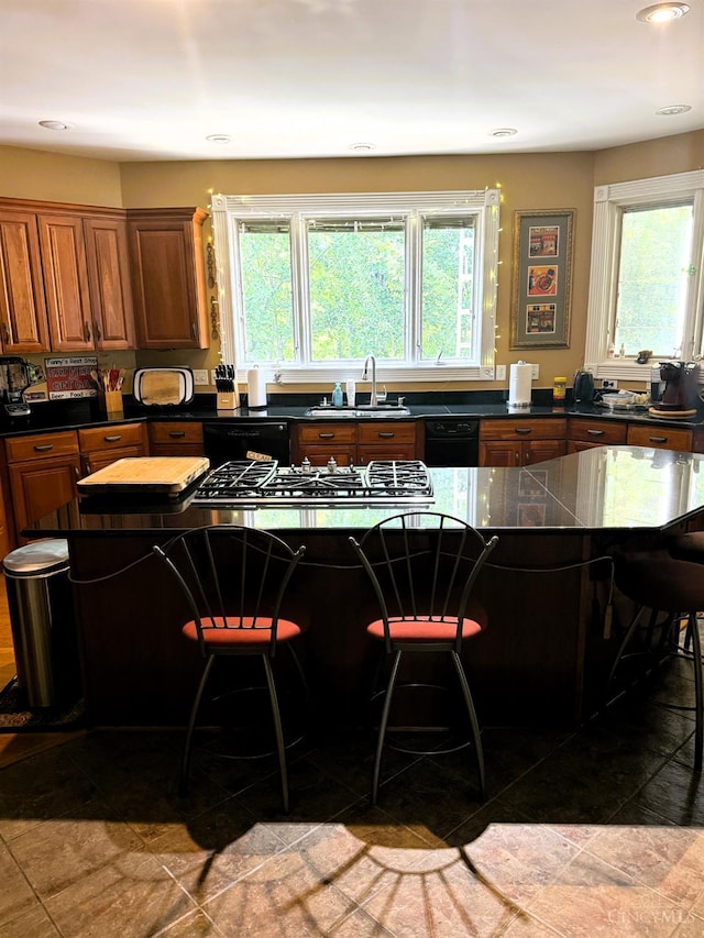 8030 Deershadow Ln, Montgomery, OH 45242 - kitchen with a breakfast bar area, dark countertops, stainless steel cooktop, brown cabinets, and black dishwasher
