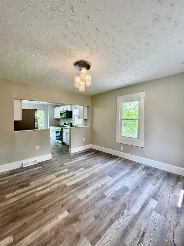 3501 Mcfarlan Rd, Cincinnati, OH 45211 - unfurnished living room with a textured ceiling, a chandelier, and dark wood-type flooring