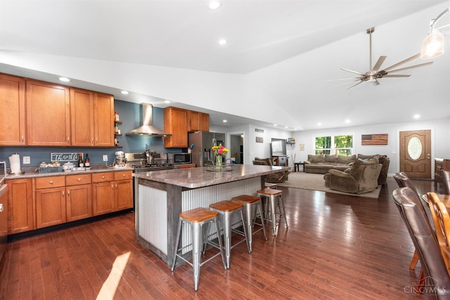 6226 Hunt Rd, Wayne Twp, OH 45118 - kitchen featuring wall chimney exhaust hood, stainless steel appliances, lofted ceiling, brown cabinets, and a breakfast bar area