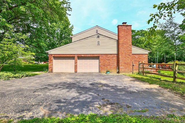 10730 Adventure Ln, Montgomery, OH 45242 - view of side of property with asphalt driveway, a chimney, a garage, and brick siding