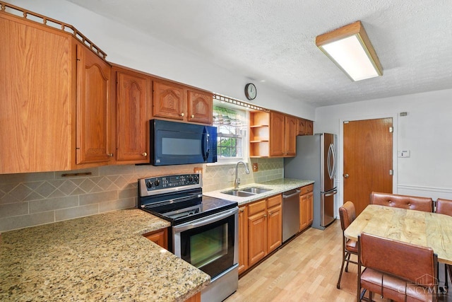 1704 Ludlow Cir, Pierce Twp, OH 45102 - kitchen with stainless steel appliances, brown cabinetry, a textured ceiling, backsplash, and light wood-type flooring
