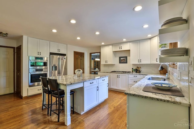 9396 Kemper Grove Ln, Symmes Twp, OH 45140 - kitchen with stainless steel appliances, a kitchen breakfast bar, white cabinets, a center island, and light stone counters