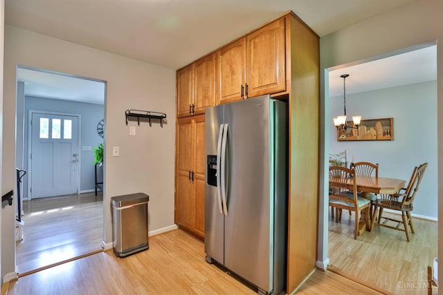 10569 Gloria Ave, Cincinnati, OH 45231 - kitchen featuring stainless steel fridge, light wood finished floors, a chandelier, brown cabinetry, and pendant lighting