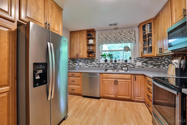 10569 Gloria Ave, Cincinnati, OH 45231 - kitchen with stainless steel appliances, open shelves, light wood-type flooring, decorative backsplash, and brown cabinetry
