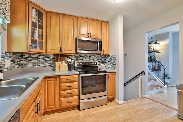 10569 Gloria Ave, Cincinnati, OH 45231 - kitchen with stainless steel appliances, light wood-type flooring, decorative backsplash, and glass insert cabinets