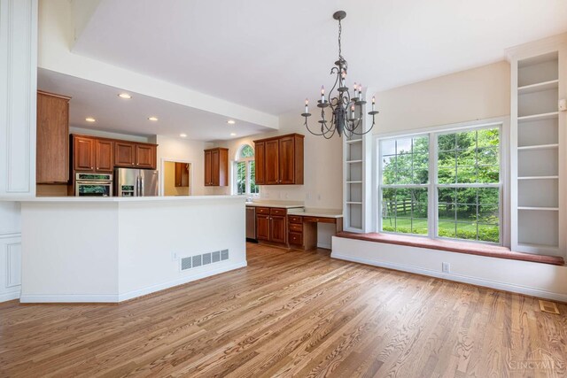7194 Orchard View Ln, Salem Twp, OH 45152 - kitchen with appliances with stainless steel finishes, a chandelier, brown cabinets, light wood-style floors, and plenty of natural light