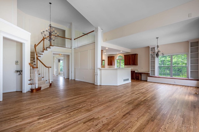 7194 Orchard View Ln, Salem Twp, OH 45152 - unfurnished living room featuring a chandelier, wood finished floors, stairs, a towering ceiling, and healthy amount of natural light