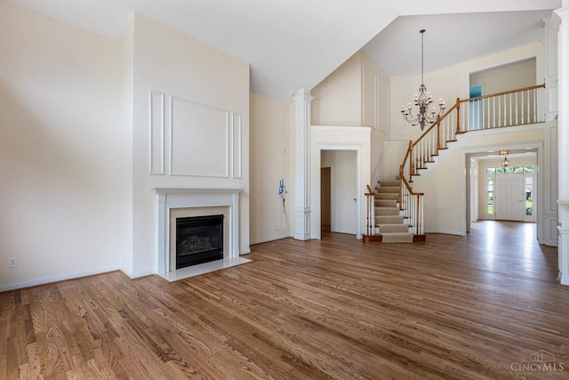 7194 Orchard View Ln, Salem Twp, OH 45152 - unfurnished living room with stairway, high vaulted ceiling, a fireplace with flush hearth, a chandelier, and wood finished floors