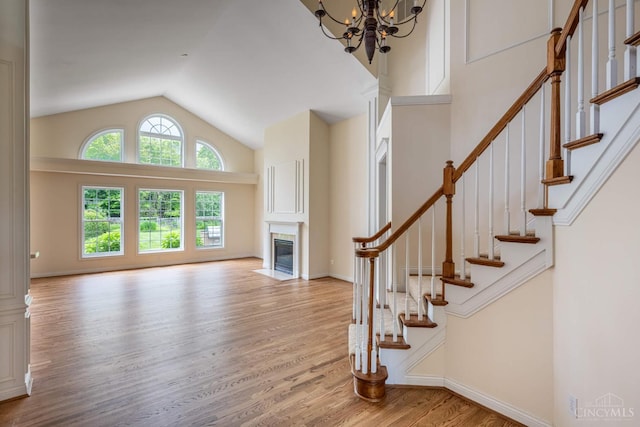 7194 Orchard View Ln, Salem Twp, OH 45152 - unfurnished living room with wood finished floors, a fireplace with flush hearth, a chandelier, high vaulted ceiling, and stairs