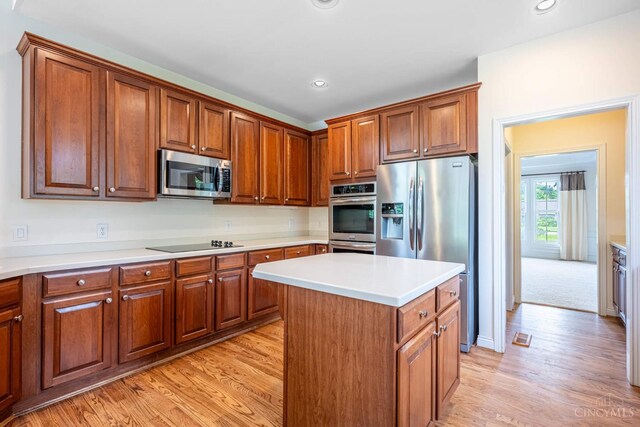 7194 Orchard View Ln, Salem Twp, OH 45152 - kitchen with appliances with stainless steel finishes, light wood-style floors, a kitchen island, brown cabinetry, and recessed lighting
