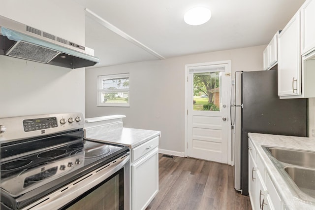 9733 Gertrude Ln, Springfield Twp, OH 45231 - kitchen with stainless steel electric stove, under cabinet range hood, dark wood finished floors, white cabinetry, and healthy amount of natural light