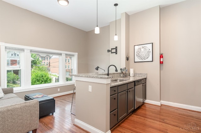 2110 Fulton Ave Unit D1, Cincinnati, OH 45206 - kitchen with dishwasher, light wood-style flooring, a peninsula, hanging light fixtures, and light stone counters