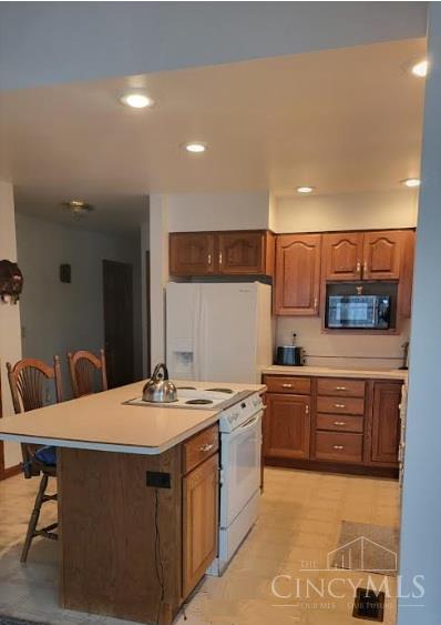 10 Chippewa Cv, Sardinia, OH 45171 - kitchen with white appliances, a breakfast bar, light countertops, brown cabinets, and recessed lighting