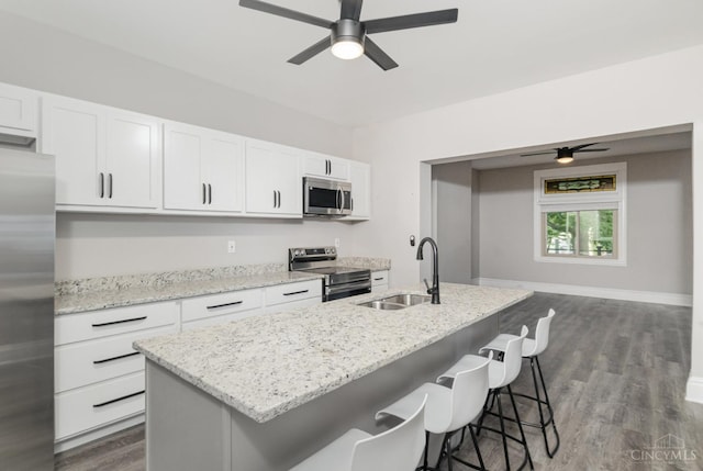 3846 Davis Ave, Cheviot, OH 45211 - kitchen featuring stainless steel appliances, a ceiling fan, a kitchen island with sink, white cabinetry, and dark wood-type flooring