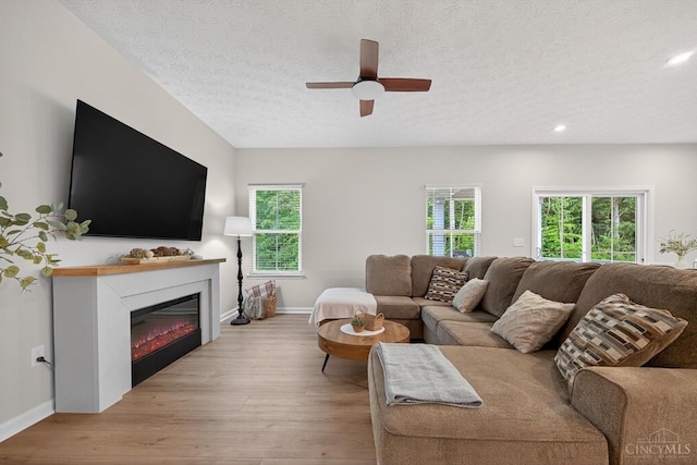1285 Millstream Dr, Batavia Twp, OH 45102 - living area featuring a textured ceiling, light wood-style floors, a ceiling fan, recessed lighting, and a glass covered fireplace