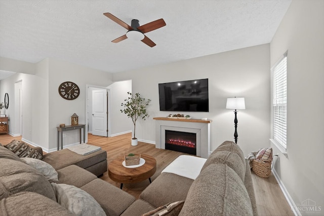 1285 Millstream Dr, Batavia Twp, OH 45102 - living area featuring light wood-style flooring, ceiling fan, a lit fireplace, and a textured ceiling