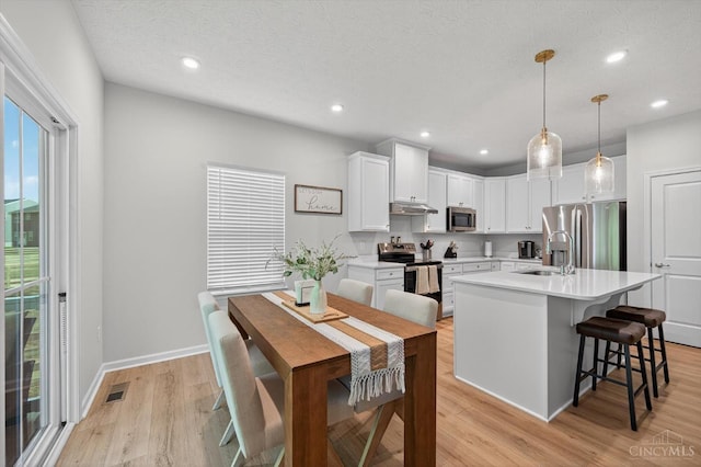 1285 Millstream Dr, Batavia Twp, OH 45102 - kitchen with stainless steel appliances, light countertops, light wood-style floors, white cabinets, and a breakfast bar area