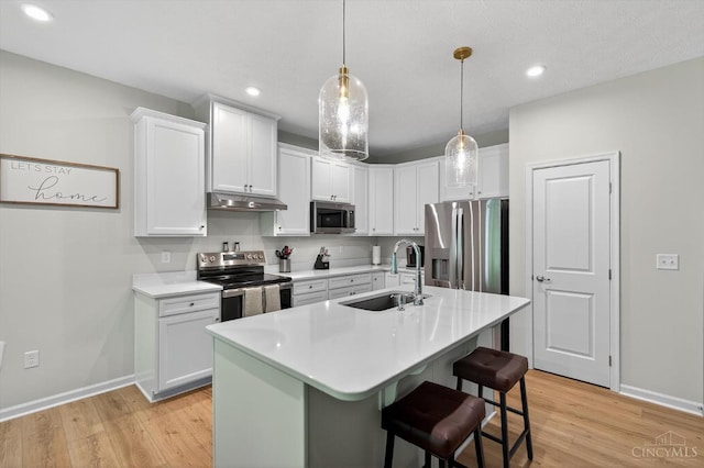 1285 Millstream Dr, Batavia Twp, OH 45102 - kitchen with appliances with stainless steel finishes, under cabinet range hood, light wood finished floors, light countertops, and white cabinetry