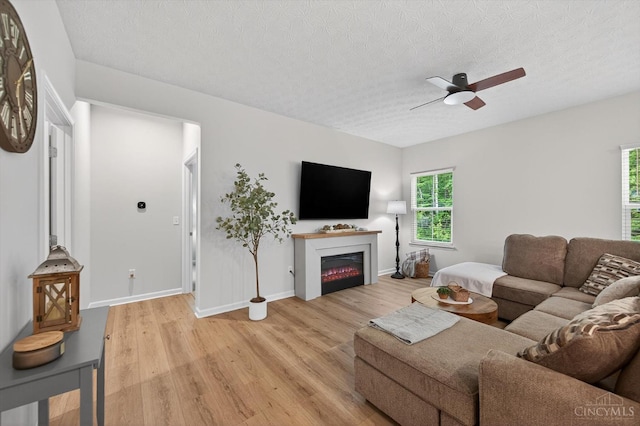 1285 Millstream Dr, Batavia Twp, OH 45102 - living area with ceiling fan, light wood-style flooring, a glass covered fireplace, and a textured ceiling